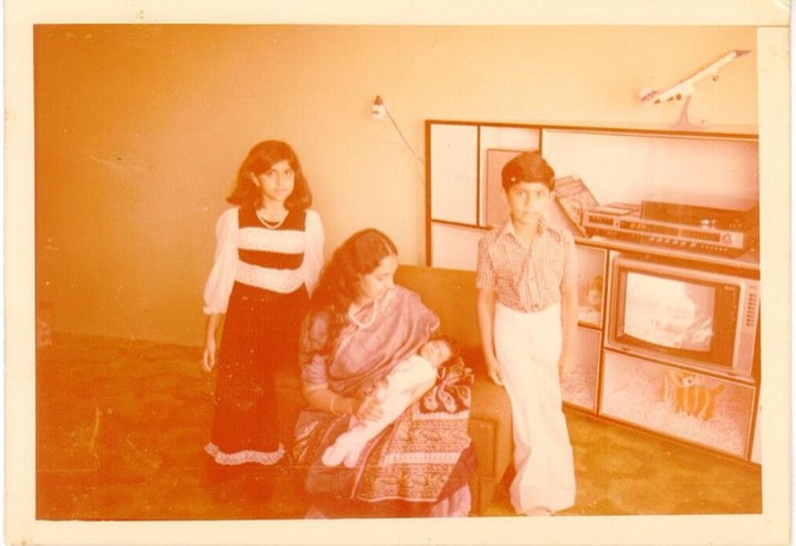 1970s photo inside the flat: mother holding a newborn, two children, a television set