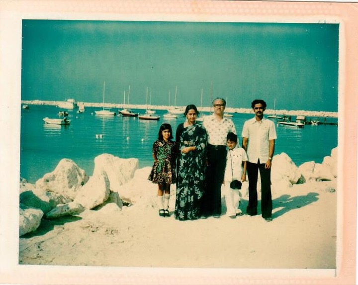 1970s photo of the family on a beach by a harbour with small boats