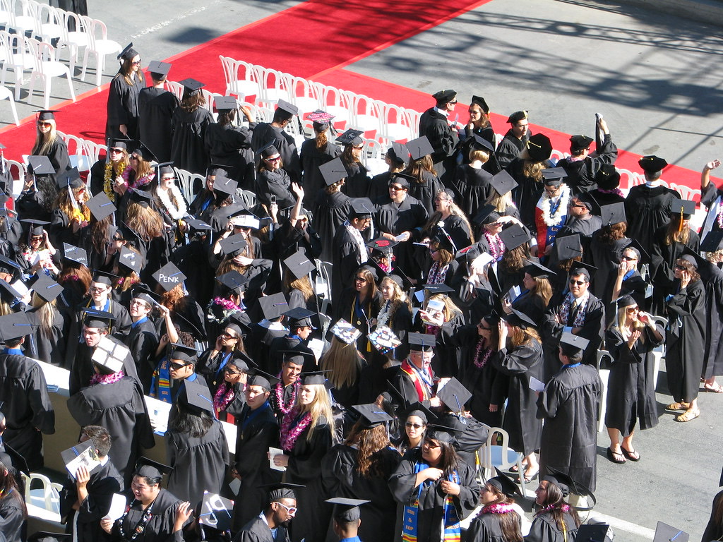 Aerial view of graduates in caps and gowns filing into a commencement ceremony