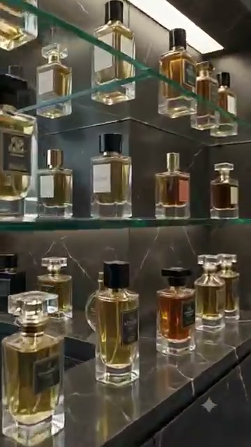 Lit glass shelves of amber perfume bottles