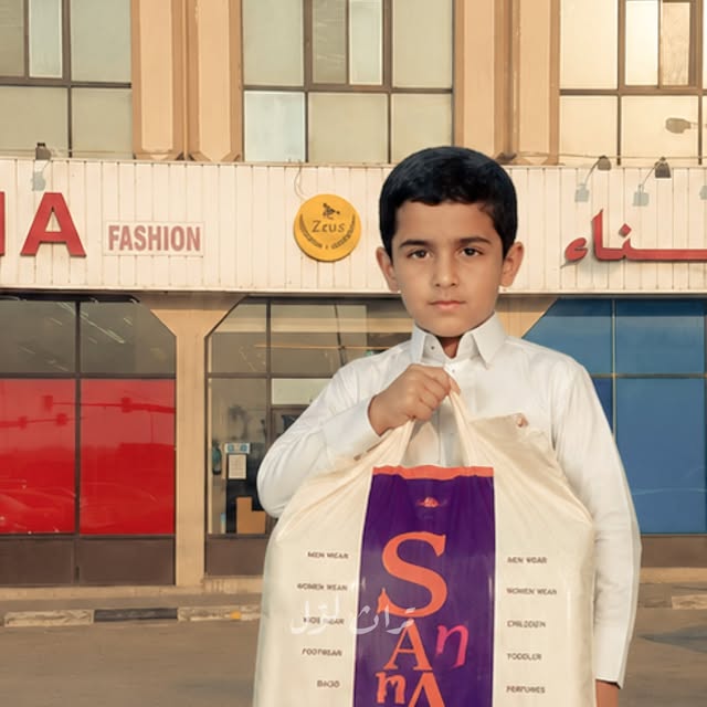 A boy holding a SANA Fashion shopping bag in front of the SANA storefront